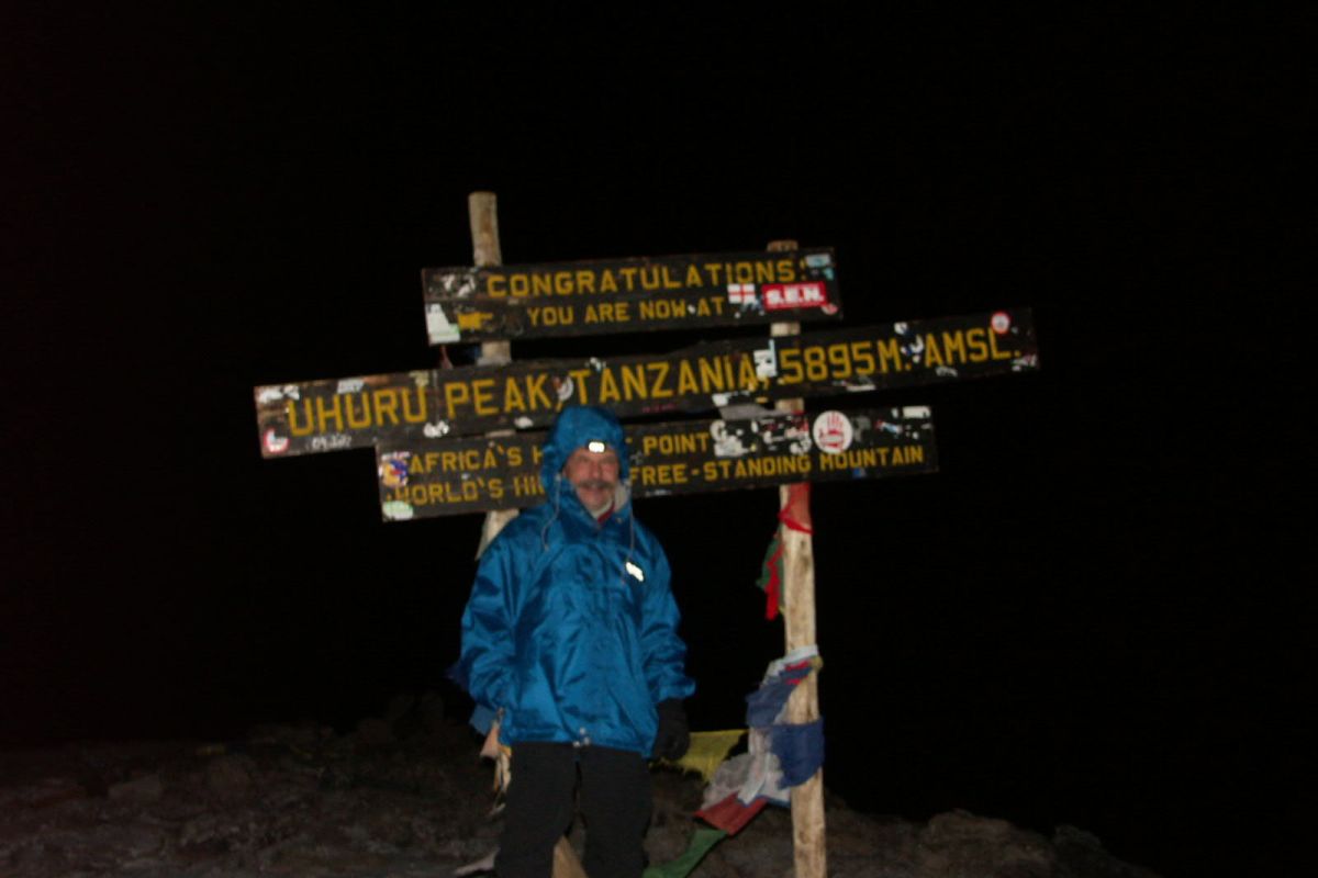 Herrliche Landschaft rund um den Kilimanjaro mit grasbewachsenen Hügeln und majestätischem Vulkan, umgeben von Wolken