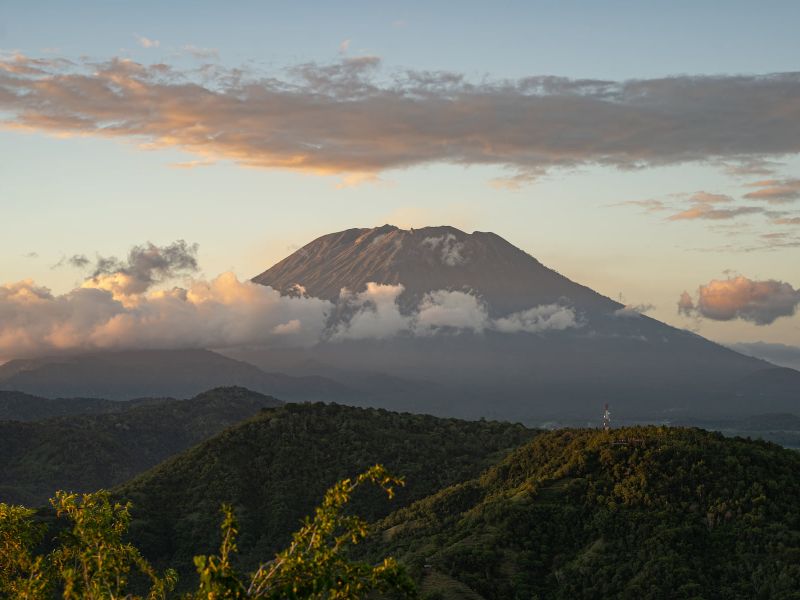 Herrliche Landschaft rund um den Kilimanjaro mit grasbewachsenen Hügeln und majestätischem Vulkan, umgeben von Wolken