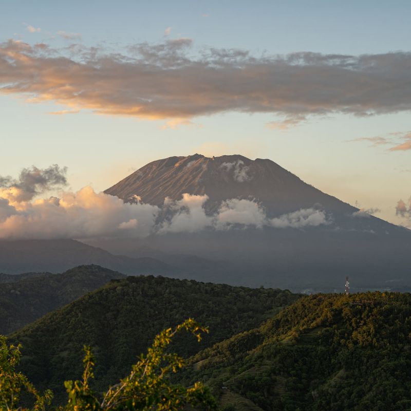 Herrliche Landschaft rund um den Kilimanjaro mit grasbewachsenen Hügeln und majestätischem Vulkan, umgeben von Wolken