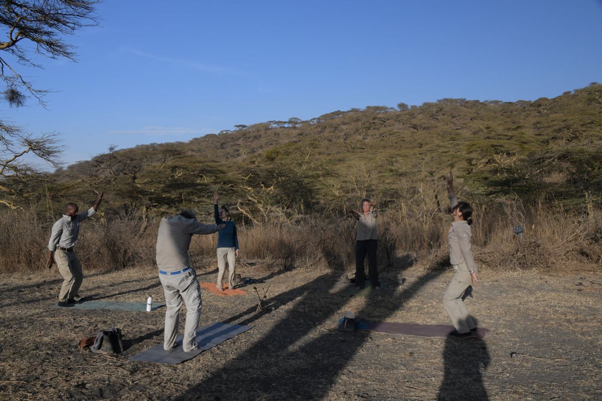 Silhouette einer Frau, die Yoga im Sand bei Sonnenaufgang praktiziert