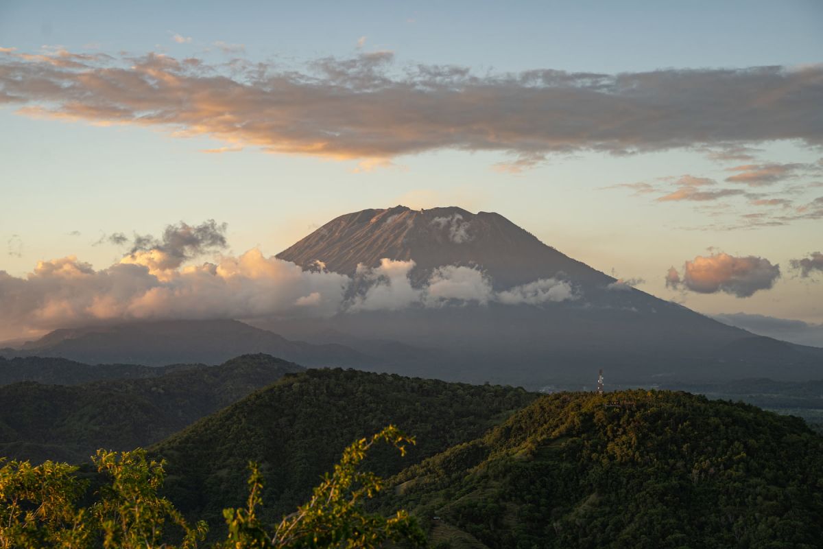 Herrliche Landschaft rund um den Kilimanjaro mit grasbewachsenen Hügeln und majestätischem Vulkan, umgeben von Wolken