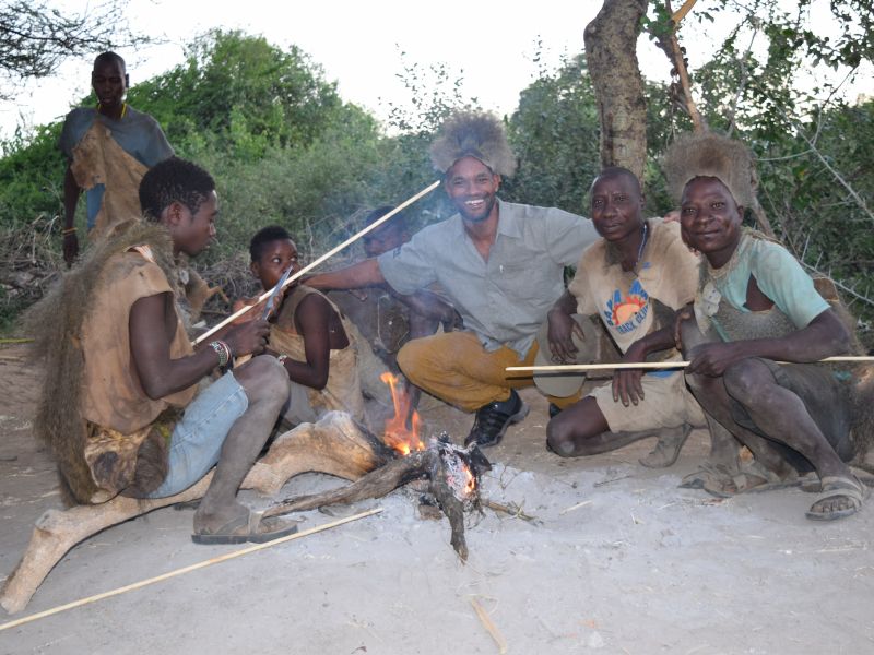 Reiseleiter zusammen mit Stammesmitglieder am offenen Lagerfeuer